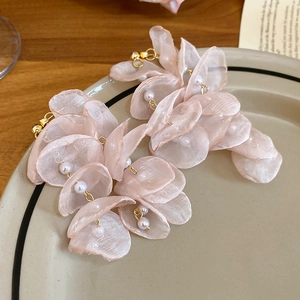 Detail of pink chiffon flower earrings with pearls and gold tassels on a ceramic plate