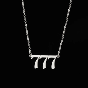 Macro shot of silver stainless steel 777 angel number pendant on a black background