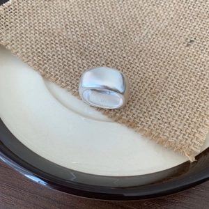 Detail of S925 sterling silver frosted wide ring on ceramic plate and rustic burlap