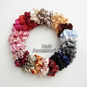 Flat lay of colorful satin scrunchies in various floral prints and solid colors