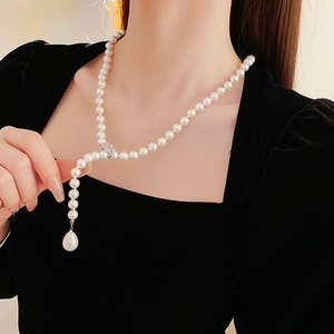 Detail of elegant pearl Y-necklace with zircon leaf and drop-shaped pearl pendant