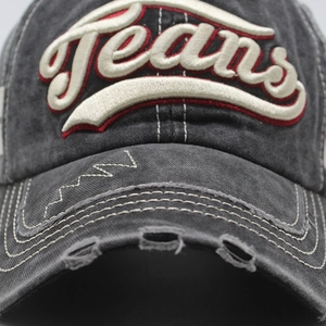 Detailed close-up of vintage washed denim baseball cap with 3D Jeans embroidery and worn edges