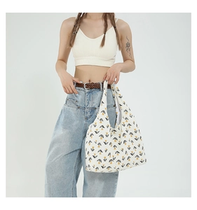 Detail shot of white canvas tote bag with yellow tulip prints on female model