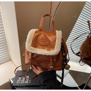 Close-up of brown faux leather backpack with white shearling trim and bell accessory