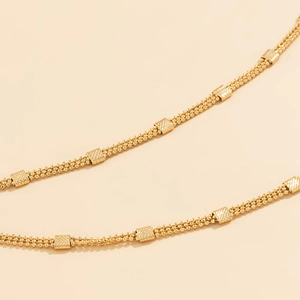 Detailed macro of gold-tone triple strand bead waist chain with textured square blocks