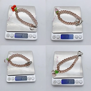 Close-up of pink translucent beaded charms with fruit pendants on a weighing scale