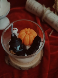 Close-up of Halloween scented candle with wax pumpkin, witch, and bat decorations