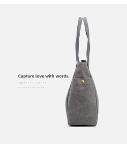 Detail shot of grey canvas tote bag showing textile texture and side pocket with metal buckle