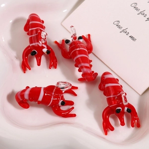 Macro view of four red glass lobster charms with white stripes in a white heart-shaped plate