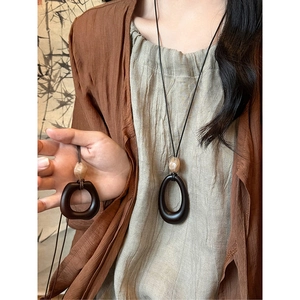 Detail of wooden resin oval pendant with vintage bead on long sweater necklace