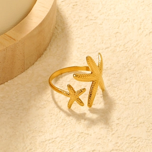 Makroaufnahme von doppeltem Seestern-Ring in Goldoptik mit Metallglanz auf Stein