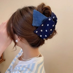 Close-up of a sweet polka dot and denim fabric bow hair clip on a model's hair