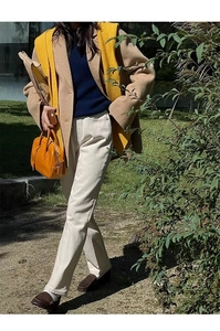 Detail of yellow scarf cape paired with beige coat and blue sweater for autumn style