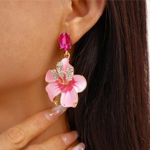 Primo piano di orecchini a fiore vintage con smalto rosa e cristalli su orecchio modella