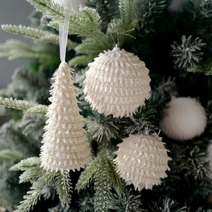 White beaded Christmas foam ornaments hanging on green tree branches for festive decor
