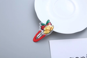 Detail of Christmas bell hair clip with golden glitter inside a transparent acrylic star