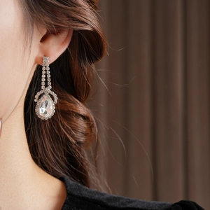Close-up of sparkling long tassel drop earrings with pear-cut rhinestone on a female model
