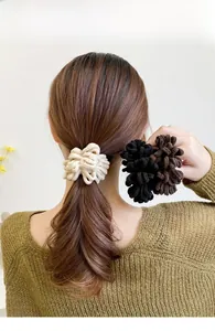 Close-up of thick knitted plush scrunchies in cream, black and brown for women