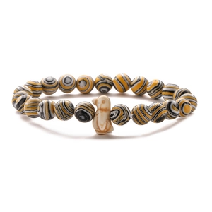 Close-up of tiger eye beads stretch bracelet with a cute beige penguin charm