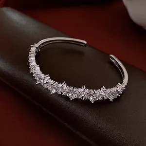 Silver-tone C-shaped cuff bracelet with irregular zircon inlay on deep leather background
