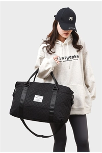 Close-up of black quilted travel bag with adjustable strap and LifeLong logo patch