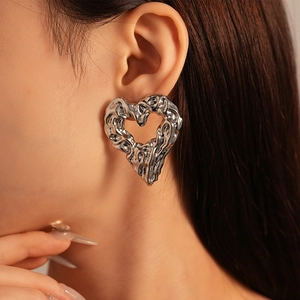 Detail view of silver heart earrings with textured lava effect and molten metal finish