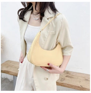 Detail of pale yellow nylon hobo bag featuring a smooth half-moon shape and shoulder strap