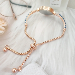 Detail of rose gold bracelet watch with blue accents and adjustable slider clasp