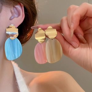 Detail of irregular gold metal earrings with marble resin pendants in three pastel colors