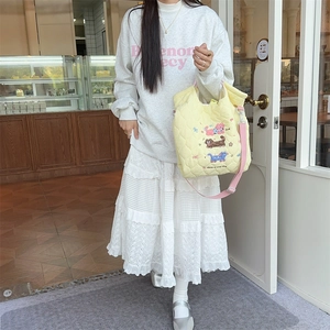 Detail of yellow quilted tote bag featuring cartoon cat embroidery and pink shoulder strap