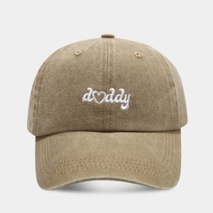Detailed view of white 'daddy' embroidery with heart-shaped 'a' on khaki washed cotton cap