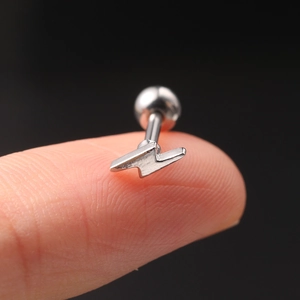 Macro shot of silver lightning bolt stud earring with ball screw back on fingertip