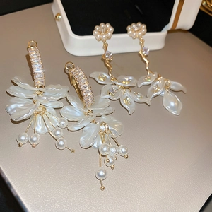 Detailed close-up of pearl flower drop earrings with sparkling zircon and gold tassel