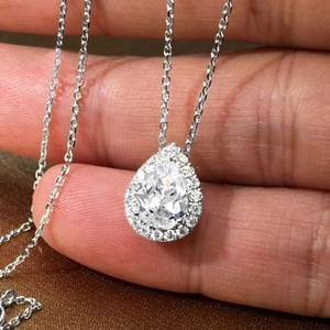 Detailed view of a silver pear-cut emerald zirconia necklace held in hand close-up