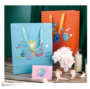 Détail de sacs cadeaux sirène et monstre avec cartes sur une table en bois