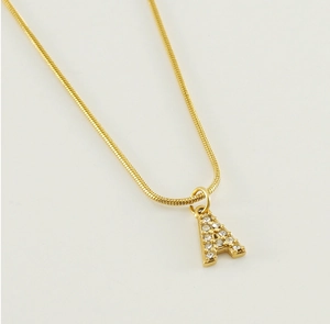 Detail of a gold snake chain necklace with a crystal-encrusted letter A pendant