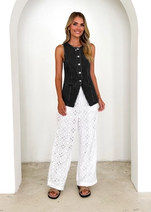 Detail of vintage black denim vest with white hollow-out lace trousers on a model