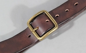 Macro view of vintage dark brown leather belt with brass square pin buckle detail