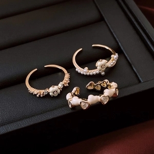 Detail of 14K gold plated flower heart and pearl rings set on black leather texture