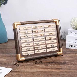 Macro shot of walnut wood ring display tray with cream velvet lining and gold metal corners
