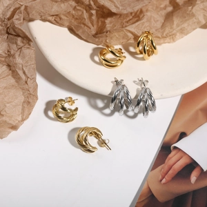 Detailed view of layered twisted hoop earrings in polished gold and silver finishes