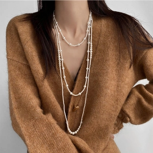 Close-up of triple-layered pearl necklace with satin luster on a vintage brown cardigan