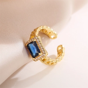 Detail of vintage gold ring with blue rectangle gem and woven band on silk background