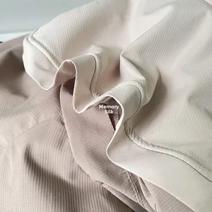 Macro view of light beige and grey pink memory fabric with fine twill texture and folds