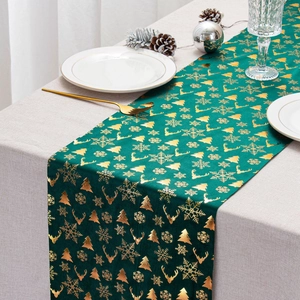 Detailed close-up of festive green velvet table runner with gold reindeer and snowflake prints