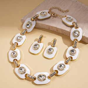 Detailed view of vintage gold-tone oval enamel necklace and matching earrings on stone