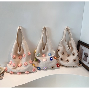 Detailed shot of three cream knit tote bags with colorful handmade floral crochet patterns