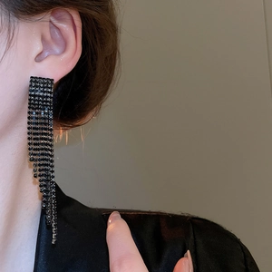 Détail de longues boucles d'oreilles à franges noires et strass portées par un mannequin