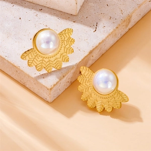Golden fan-shaped leaf earrings with white pearls on elegant stone background