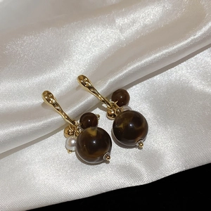 Detailed view of vintage gold drop earrings with brown marble resin beads and white pearl accent